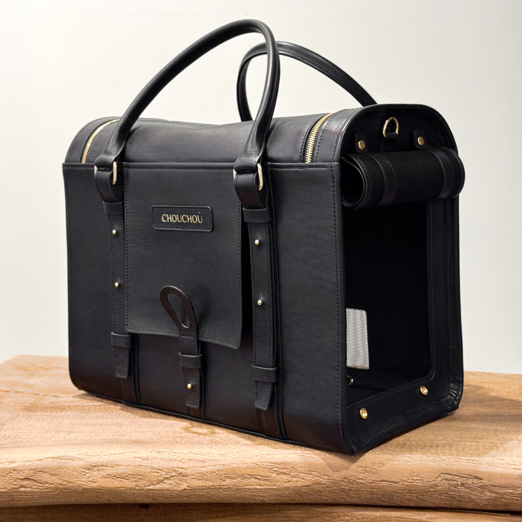 Integrated luggage trolley sleeve allows the dark leather pet carrier to rest effortlessly on a suitcase handle during busy airport navigation.