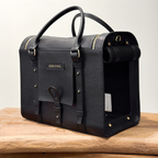 Integrated luggage trolley sleeve allows the dark leather pet carrier to rest effortlessly on a suitcase handle during busy airport navigation.
