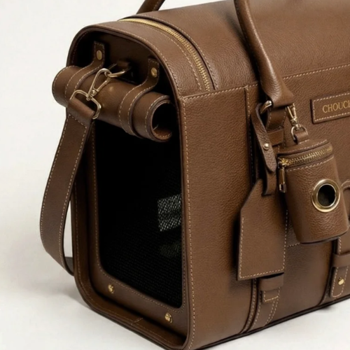 Rolled transit canopies and heavy-duty golden clasps detail the side profile of the artisan brown dog luggage, revealing the breathable interior netting.
