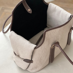 Textured beige fabric forms the structured walls of this luxury pet tote, revealing a contrasting plush dark interior designed for canine comfort.