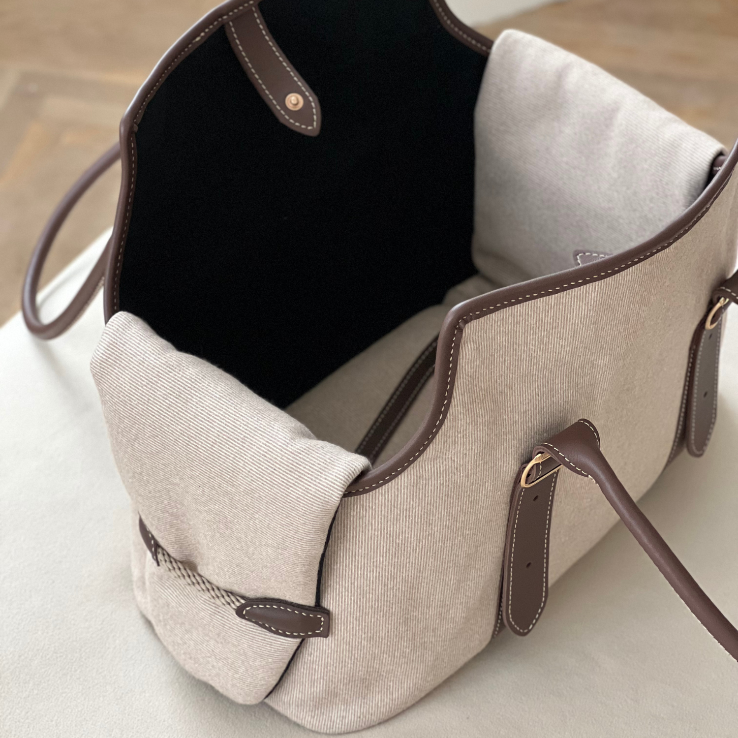 Textured beige fabric forms the structured walls of this luxury pet tote, revealing a contrasting plush dark interior designed for canine comfort.