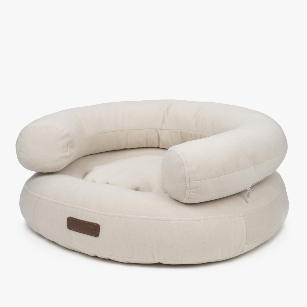 Architectural curves define the ecru pet lounge, highlighting the plush raised bolsters and durable furniture-grade textile of the CacheMio bed.