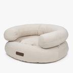 Architectural curves define the ecru pet lounge, highlighting the plush raised bolsters and durable furniture-grade textile of the CacheMio bed.