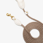 Top-down view of the coiled CacheMio & CHOUCHOÚ walking leash, showcasing the beautiful contrast between the cream leather and earthly beige rope.