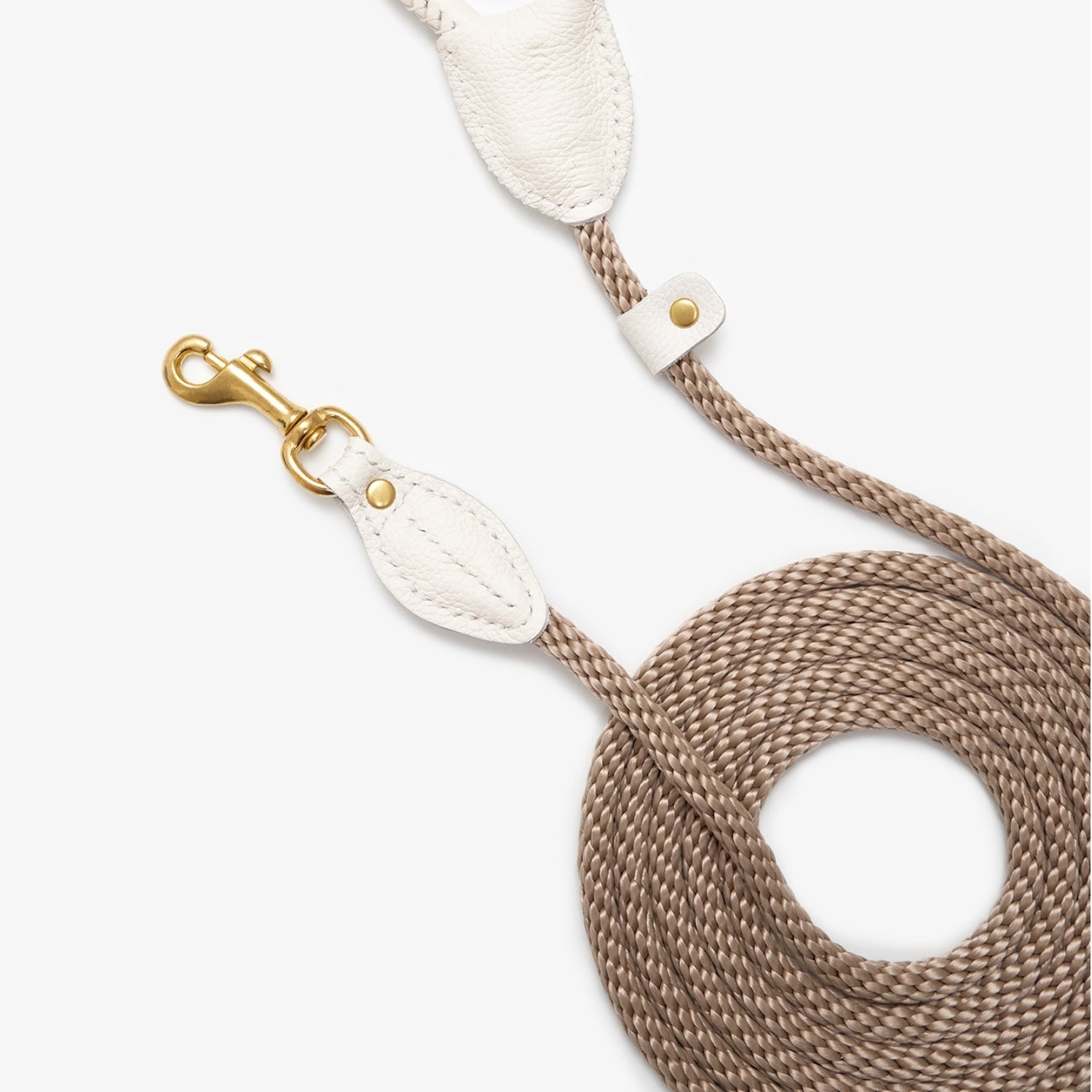 Top-down view of the coiled CacheMio & CHOUCHOÚ walking leash, showcasing the beautiful contrast between the cream leather and earthly beige rope.