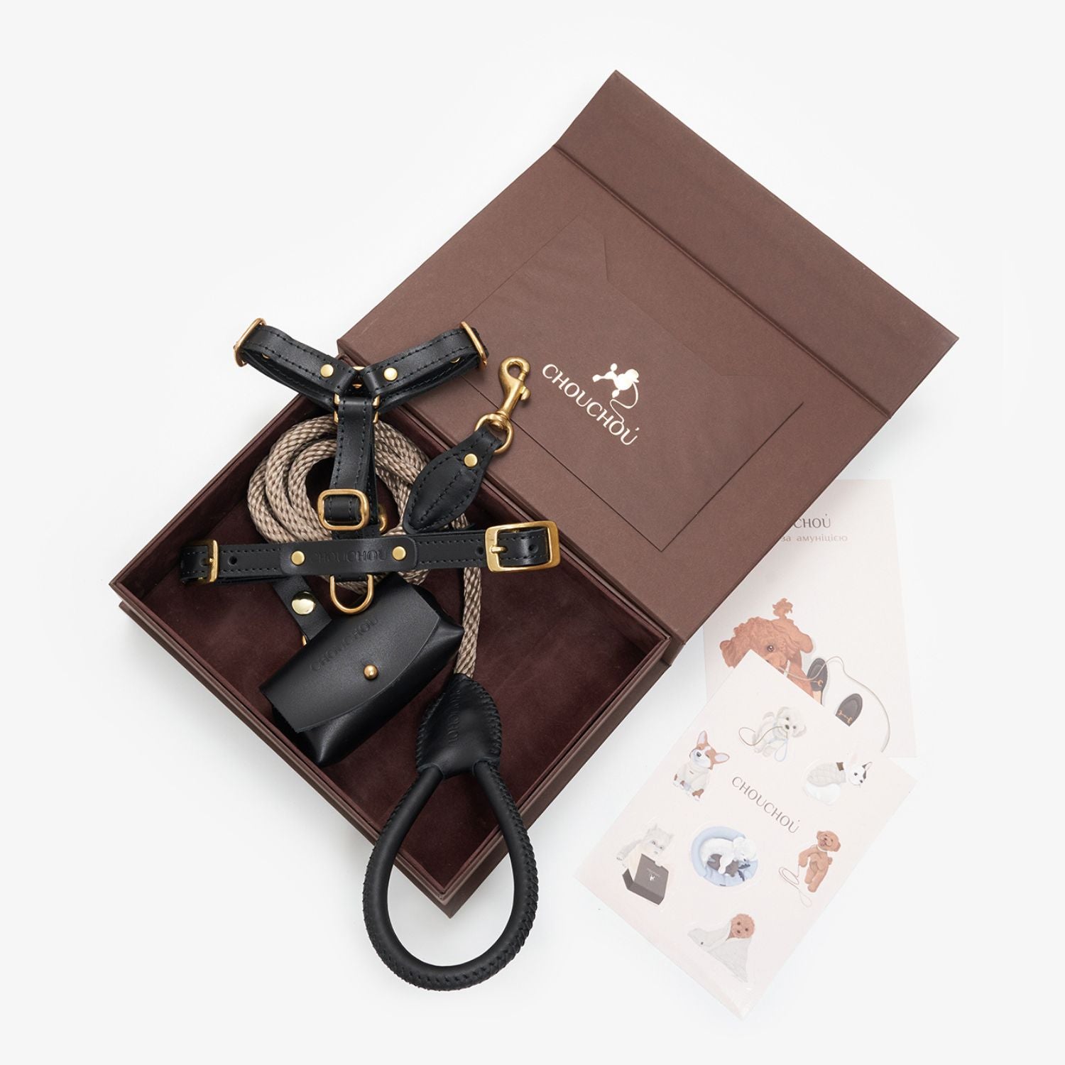 Top-down view of the luxurious black leather dog walking set by CacheMio & CHOUCHOÚ, presented in a brown gift box with care cards.