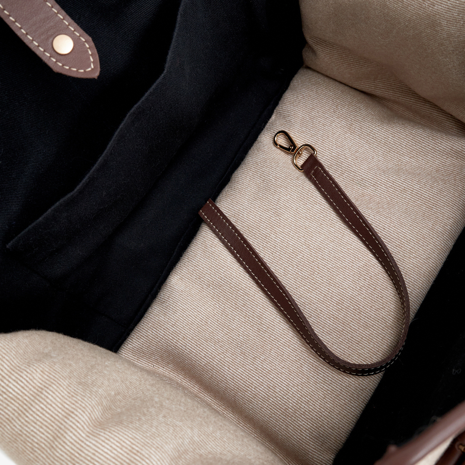 Concealed within the calming beige sanctuary, a stitched leather safety strap with a golden clasp waits to secure the canine passenger.