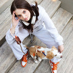 Grey tracksuit and white headphones complete the casual urban aesthetic of a dog owner resting on stone steps beside her beagle.