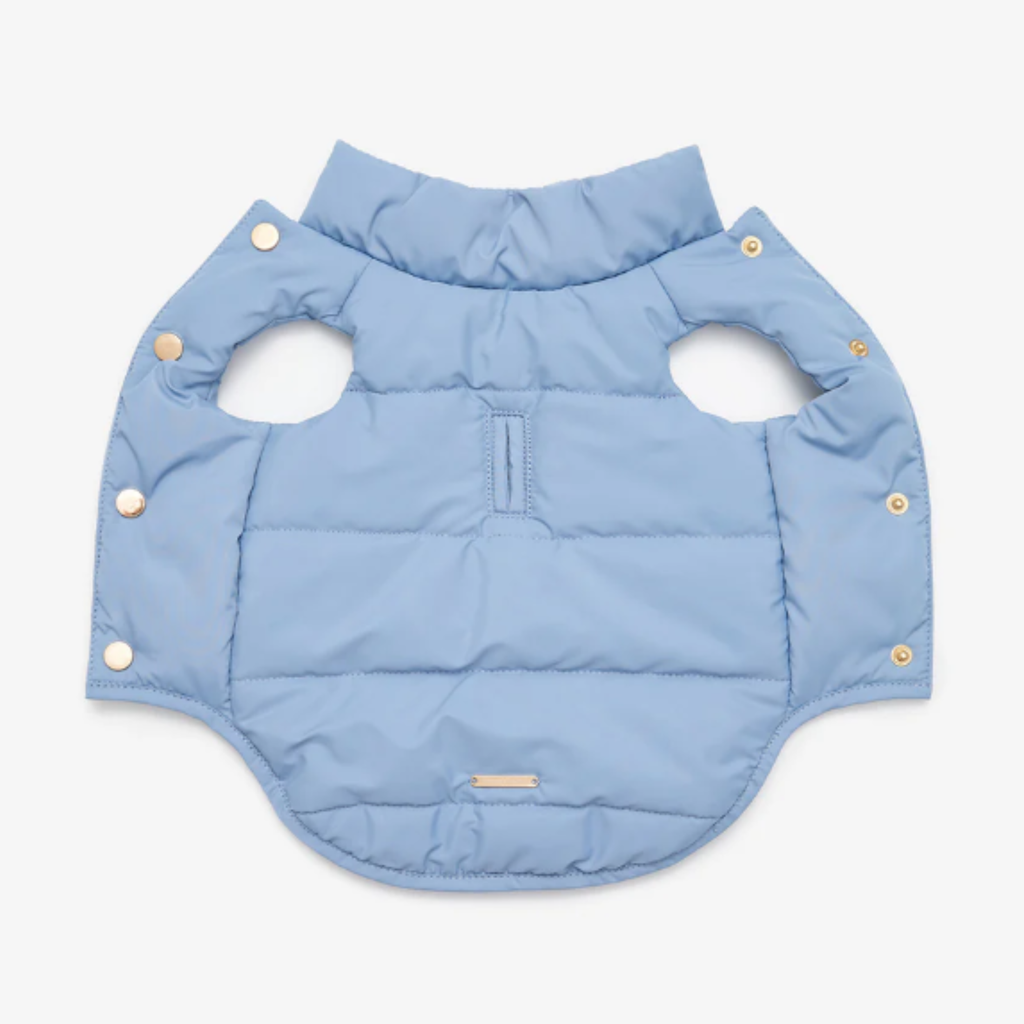 Revealing the technical core, the unfastened pastel jacket displays its evenly distributed synthetic insulation. Golden snap fasteners line the edges, promising a rapid and secure dressing experience.