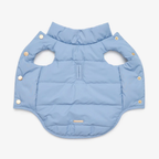 Revealing the technical core, the unfastened pastel jacket displays its evenly distributed synthetic insulation. Golden snap fasteners line the edges, promising a rapid and secure dressing experience.