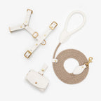 Minimalist flatlay of the complete milk white dog walking set by CacheMio & CHOUCHOÚ, featuring a leather harness, rope leash, and dispenser.