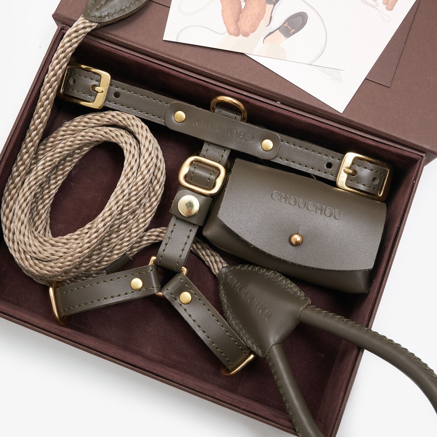 Close-up of the Olive green premium Italian leather dog harness and waste bag holder by CacheMio & CHOUCHOÚ, resting elegantly inside the signature packaging.