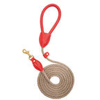 Top-down view of the coiled Classic Red walking leash by CacheMio & CHOUCHOÚ, featuring a bold red leather handle and earthly beige rope.