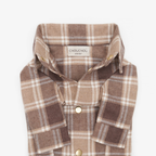 Extreme close-up of an unbuttoned brown plaid dog shirt collar, revealing the CHOUCHOÚ atelier fabric tag and metallic snap buttons.