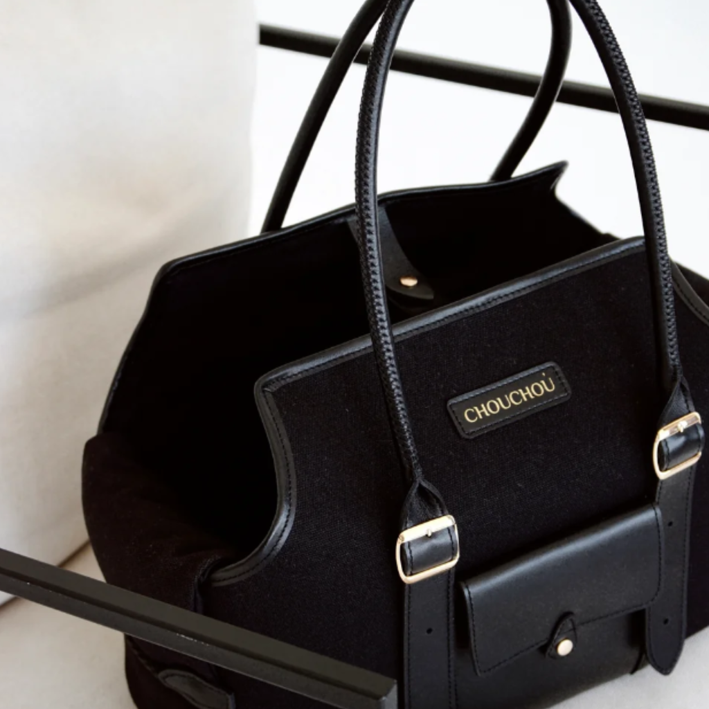 Structured top handles frame the plush, light-blocking interior sanctuary of the black designer pet tote, engineered for secure and stylish urban mobility.