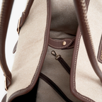 Meticulous leather binding outlines the opening of the tactile canvas pet tote, framing the internal security hardware designed for safe city mobility.