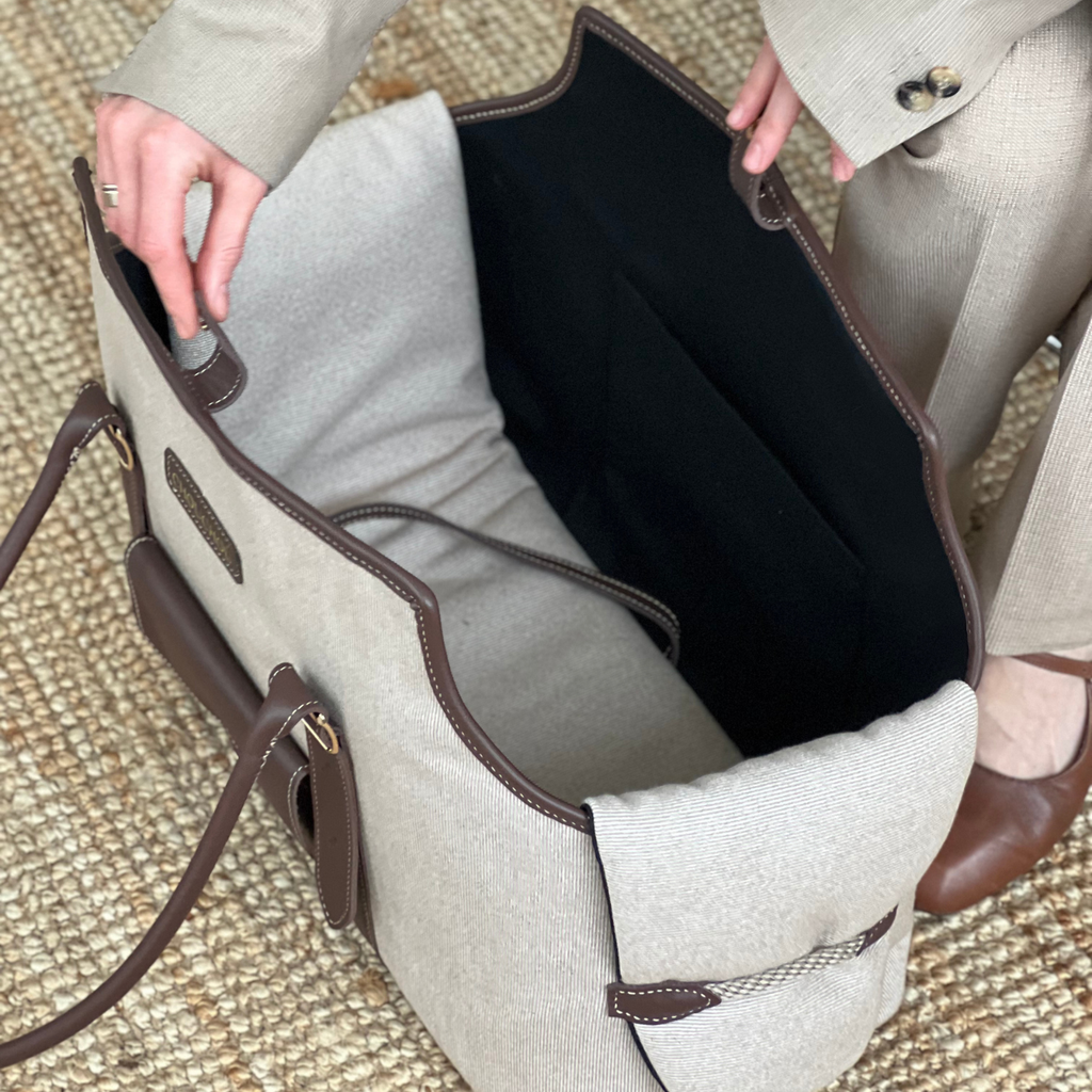 Dressed in a tailored beige suit, a stylish owner adjusts the flexible side panels of the classy canine carrier before an urban stroll.