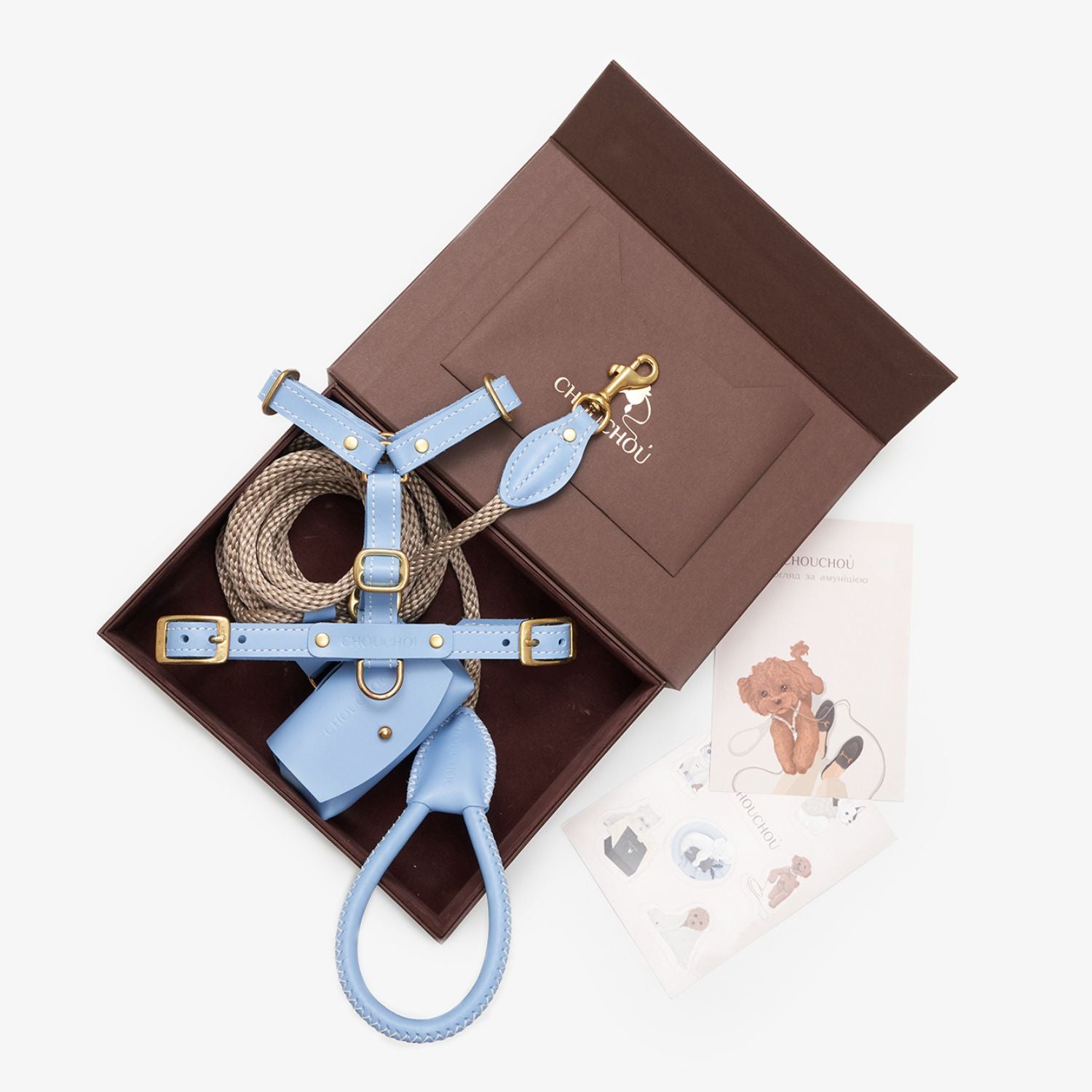 Top-down view of a luxurious light blue leather dog walking set by CHOUCHOÚ, beautifully presented in a premium brown gift box.