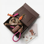 Top-down view of the vibrant Chromatique dog walking kit, highlighting a hot pink leather lead and multi-colored chest strap in bespoke packaging.